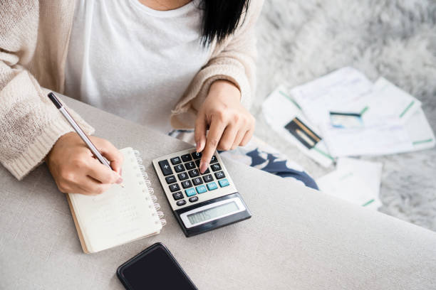 woman writing a list of debt on notebook calculating